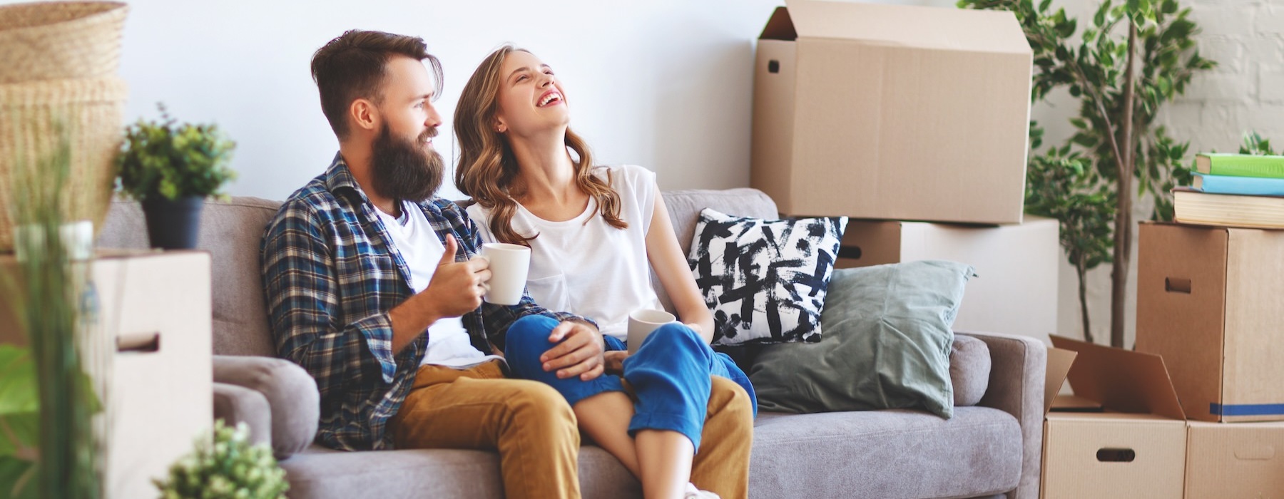 a man and a woman sitting on a couch with boxes and a coffee cup